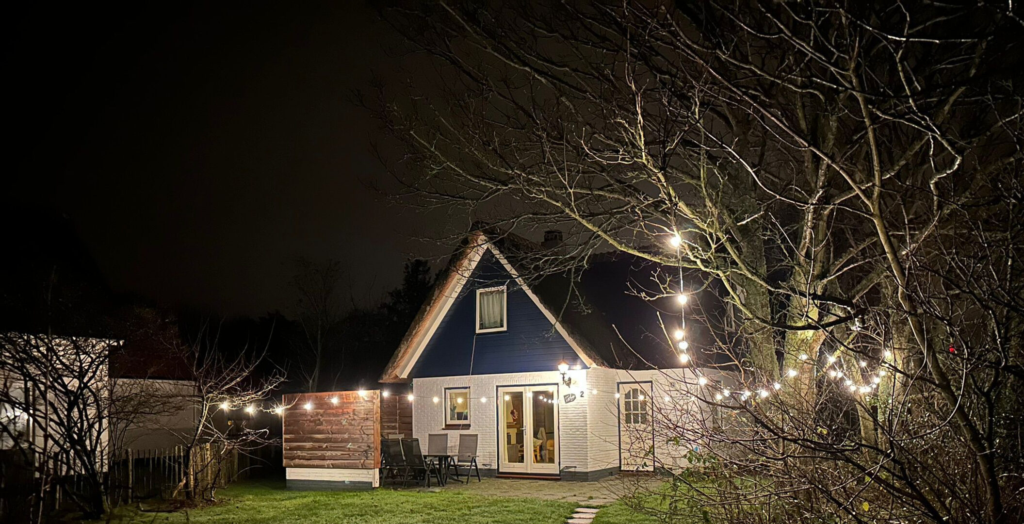Het huisje 's avonds met lichtjes in de tuin